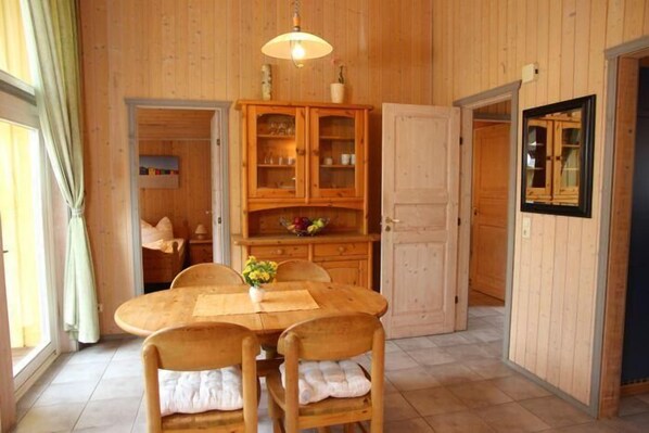 Ein Esszimmer aus Holz mit einem runden Tisch und Stühlen, einer Vitrine mit Glastüren und einer Tür zu einem anderen Raum.