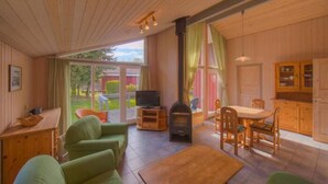 A cozy cabin with a wooden interior, a fireplace, a dining area, and a television.