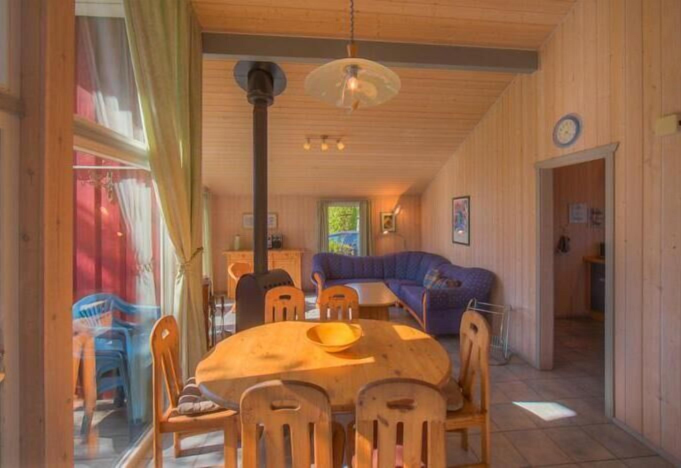 En ombonad inredning med ett matbord och stolar i trä, en soffa och en takfläkt.