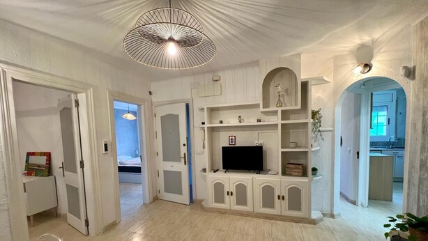 A spacious living area with a large TV, white cabinetry, and a ceiling light fixture. - Port Cambrils 11004 (Cambrils)