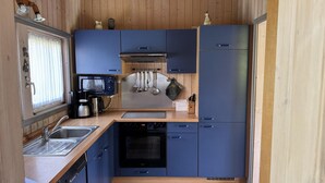 A compact kitchen with wooden cabinets, a microwave, a coffee maker, and a stove.