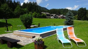 Ein Swimmingpool mit zwei Liegestühlen und einem Picknicktisch.