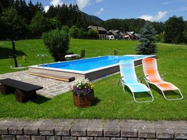 Piscina con dos sillas de descanso y una mesa de picnic.