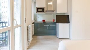 A compact kitchen with white cabinets, a microwave, and a refrigerator.
