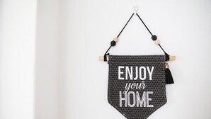 A wall-mounted sign with the text "ENJOY your HOME" in a geometric pattern.