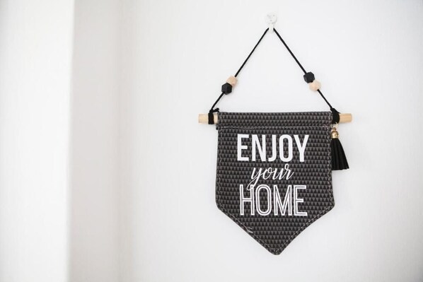 Eine Wandtafel mit der Aufschrift „ENJOY your HOME“ in einem geometrischen Muster.