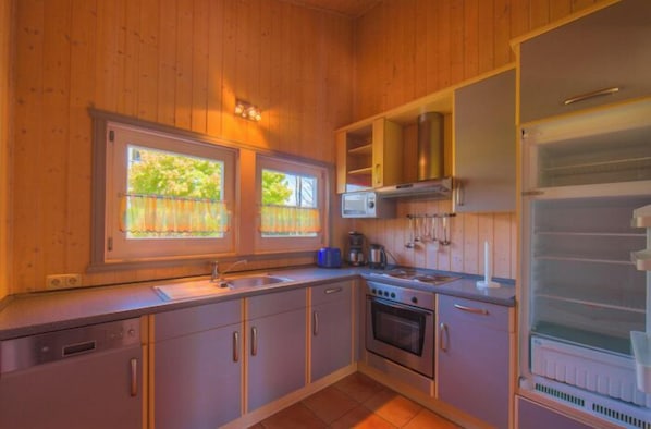 Une cuisine de taille réduite, dotée de meubles de rangement en bois, d’une cuisinière, d’un four à micro-ondes et d’un réfrigérateur.