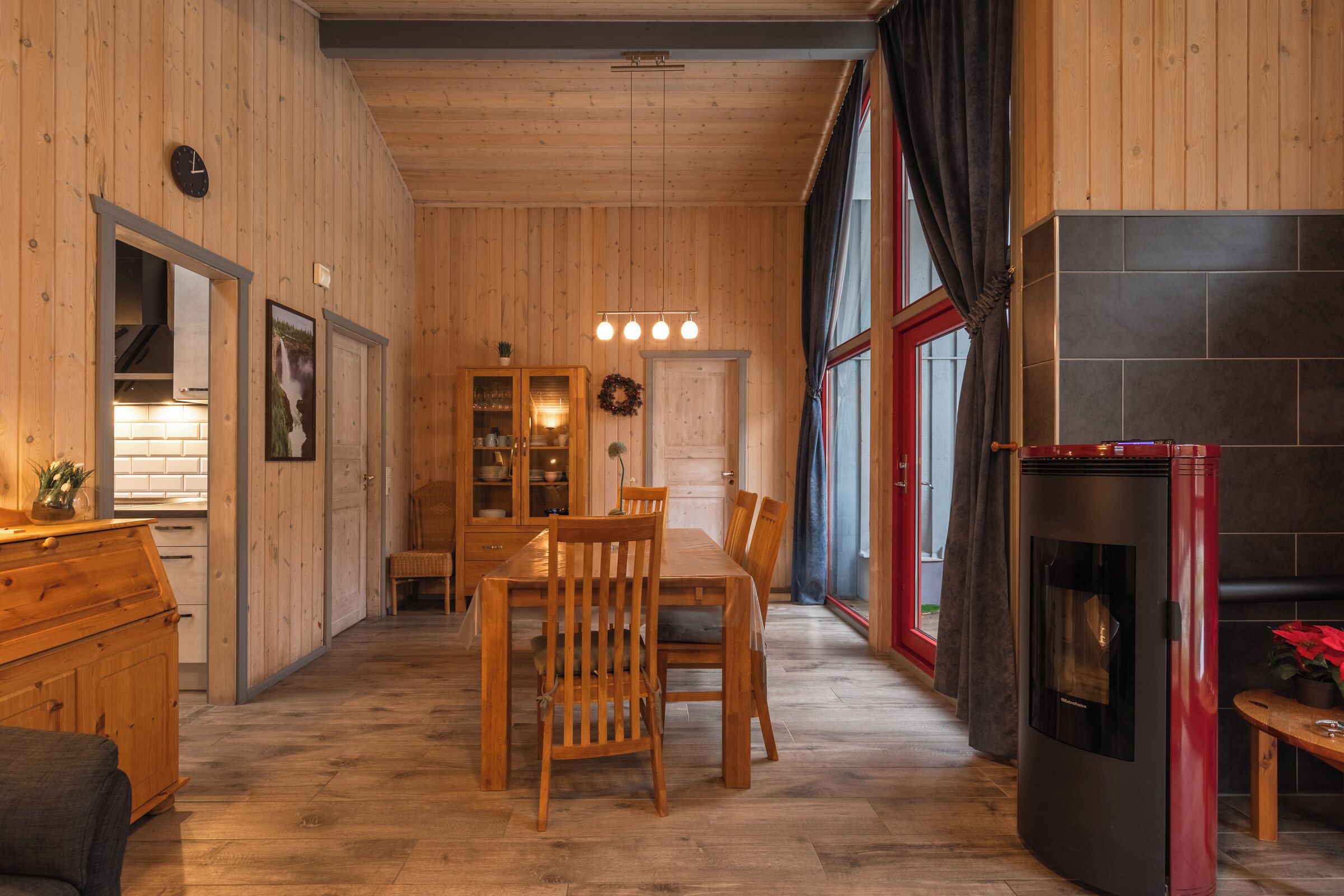 Un intérieur en bois comprenant une table à manger, des chaises, une cheminée et un coin cuisine.
