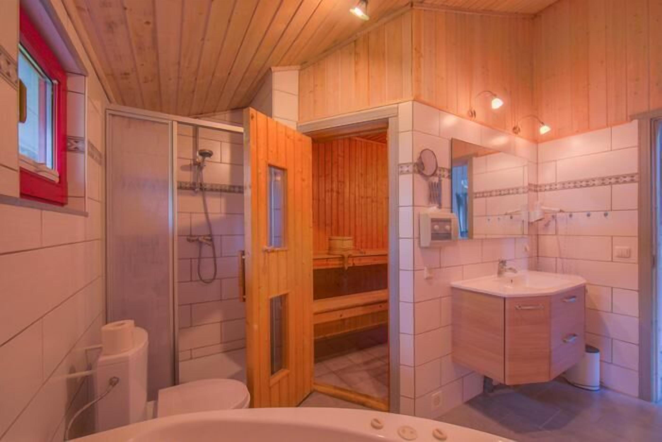 Ein Badezimmer mit Holzvertäfelung, einer Badewanne, einer Dusche und einem Waschtisch.