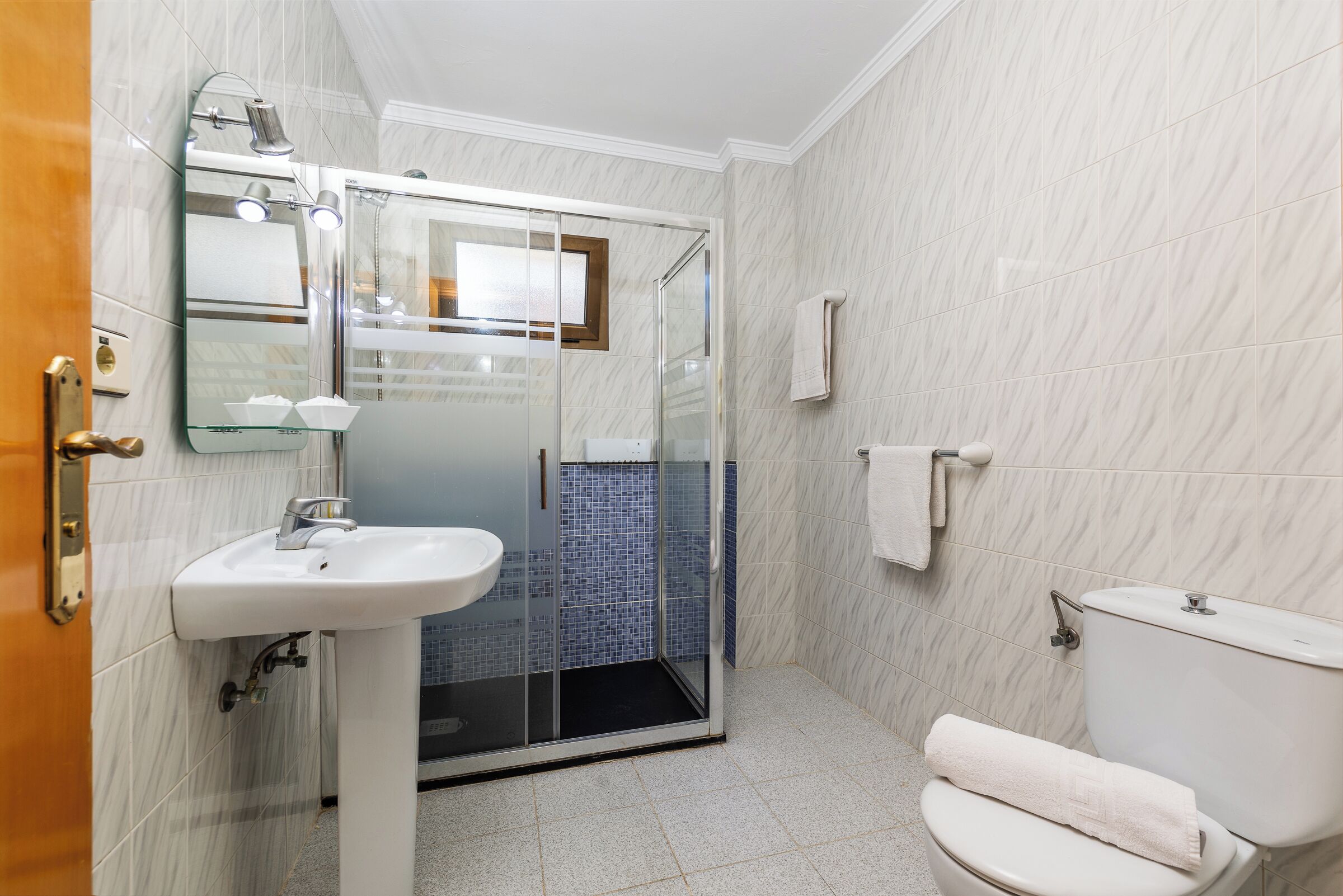 A bathroom with a glass-enclosed shower, a white sink, and a toilet.
