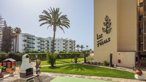 A hotel named "Las Fijas" with a modern building, a well-maintained lawn, and a palm tree. - Apartamento Los Ficus (San Bartolomé de Tirajana)