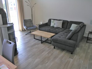 A modern living room with a grey sofa, a wooden coffee table, a grey armchair, and a tall floor lamp. - Seeschwalbe 324 - Das Skandinavische Familienhaus für 4 mit Sauna und Whirlpool (Mirow)