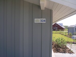 A building with a grey exterior wall and a sign indicating the address '324.' - Seeschwalbe 324 - Das Skandinavische Familienhaus für 4 mit Sauna und Whirlpool (Mirow)