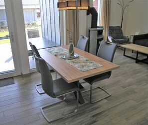 A dining area with a wooden table, grey chairs, a vase with flowers, and a lamp.