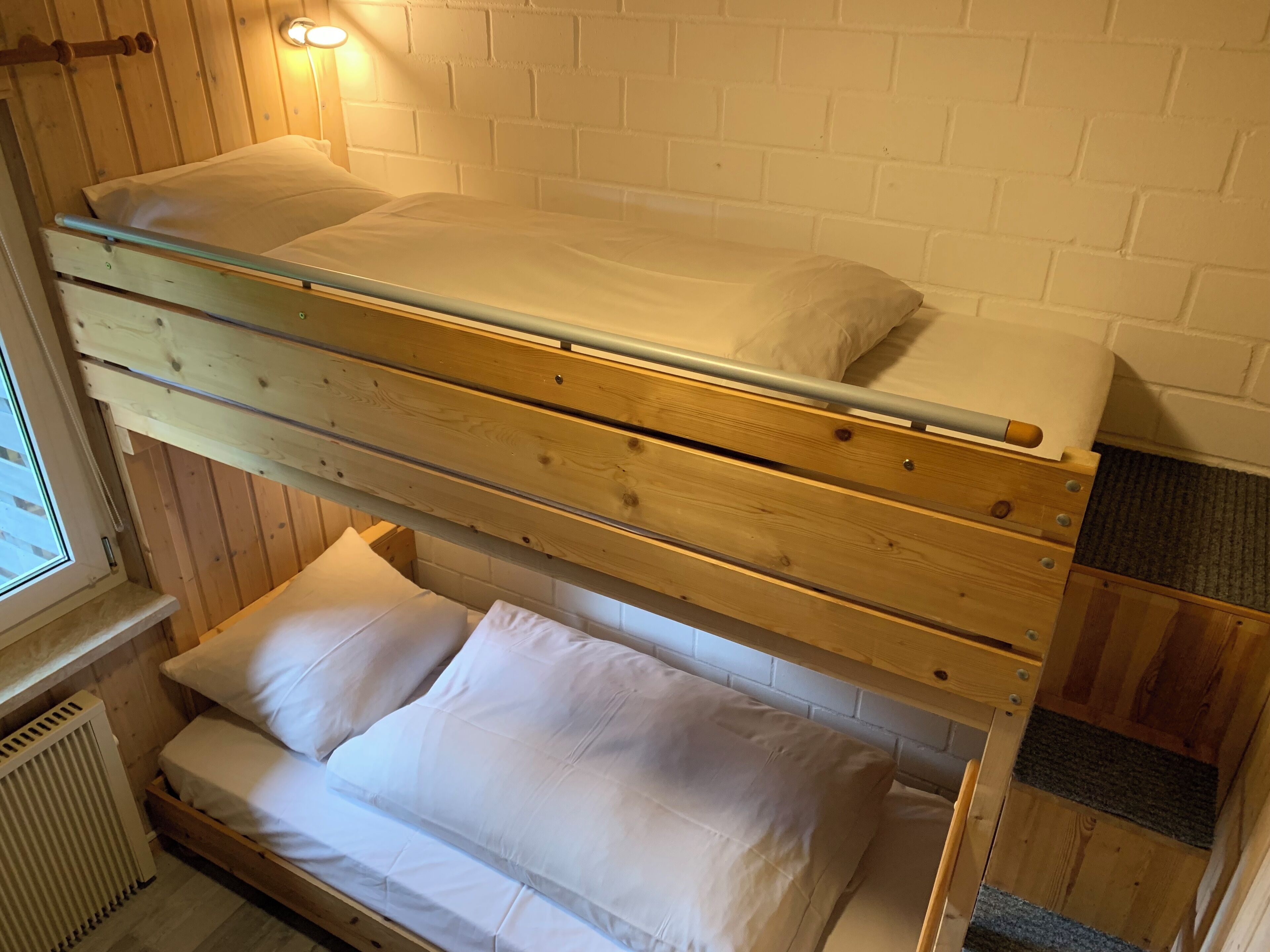 Ein Stockbett mit Holzrahmen und weißer Bettwäsche.