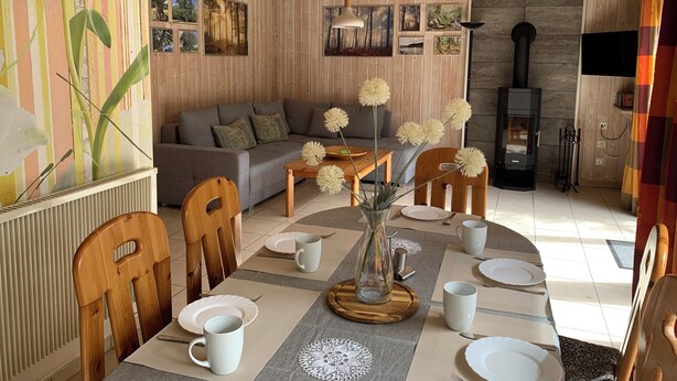 Una sala de estar acogedora con un sofá, una mesa de comedor de madera para cuatro personas y una chimenea.