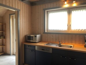 Ett kompakt kök med mikrovågsugn, diskho och inbyggd diskmaskin.