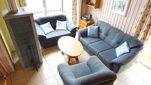 Una sala de estar con un sofá, dos sillones, una mesa de centro y una chimenea.