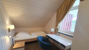 Ein kleiner, gemütlicher Raum mit einem Etagenbett, einem Schreibtisch, einem Stuhl und einem Fenster mit Vorhängen.