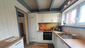 Eine kleine Küche mit weißen Schränken, einer Holz Arbeitsplatte und einem eingebauten Backofen.