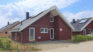 Ein rotes Gebäude mit geneigtem Dach, einem kleinen Fenster und einer Tür. Ein Parkschild mit einem 'P' und der Nummer 513 ist sichtbar.