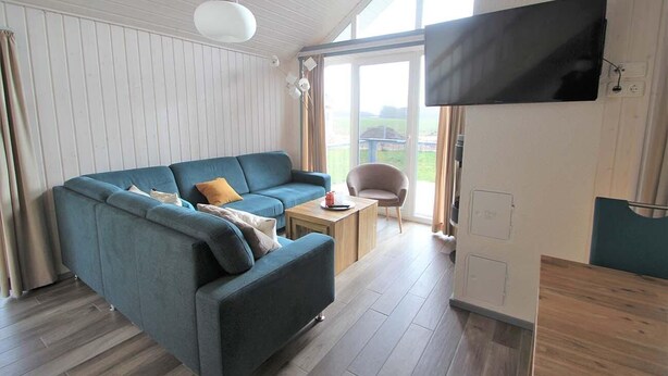 A modern living room with a blue sofa, a wooden coffee table, and a television mounted on the wall.
