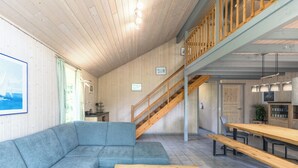 A modern interior with a wooden staircase, a sectional sofa, and a dining area with benches.