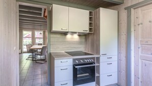 A compact kitchen with a built-in oven, a stovetop, and white cabinetry.