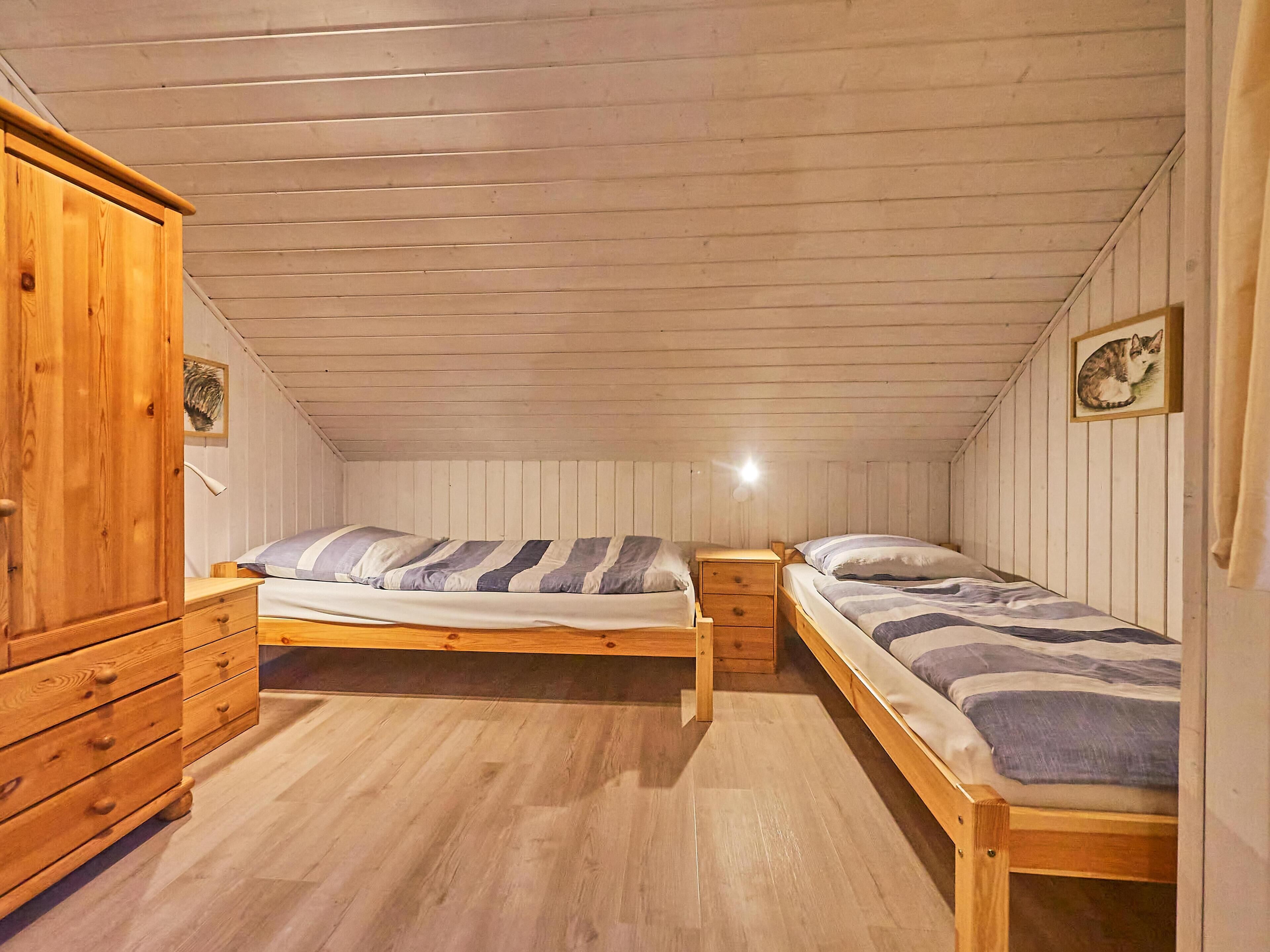 A small, cozy room with two wooden beds, a wooden wardrobe, and a small bedside table.