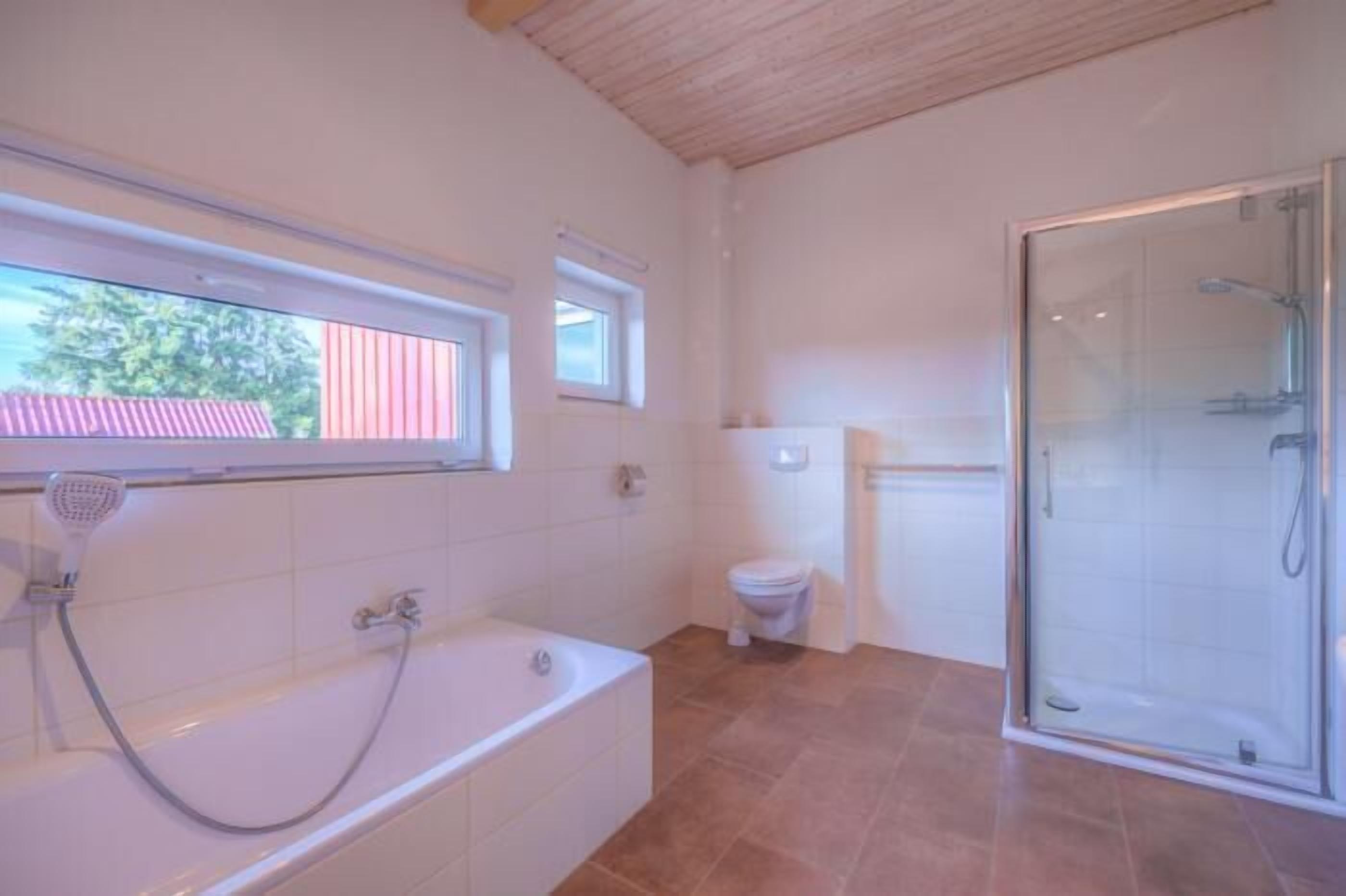 A bathroom with a bathtub, toilet, and glass shower enclosure.