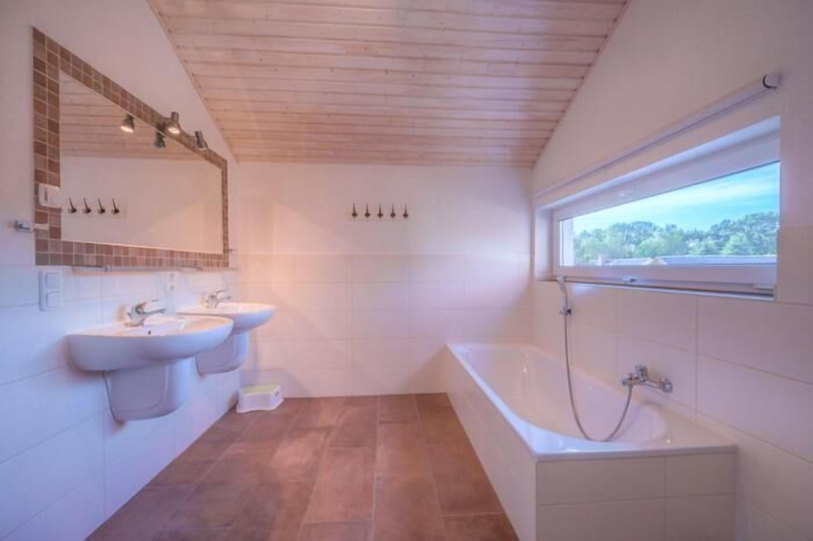 A bathroom with two sinks, a bathtub, and a large window.