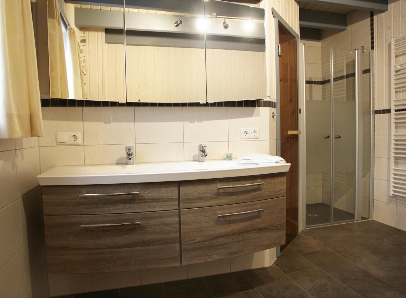 A modern bathroom with a vanity, a shower area, and a glass door.