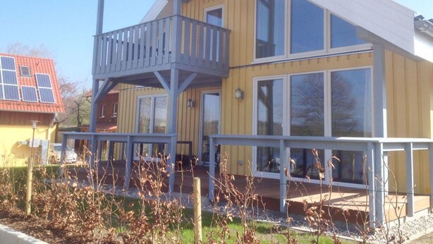 Een gebouw met twee verdiepingen, een balkon, grote ramen en een terras.