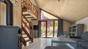 A modern interior with a wooden staircase, a sofa, a table, and a TV. - Wildgans 48 - Klassisches Skandinavisches Ferienhaus für bis zu 6 Personen (Mirow)