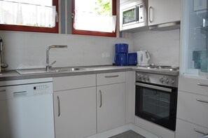 Una cucina moderna con mobili bianchi, un lavello in acciaio inossidabile, una macchina per il caffè e un forno.