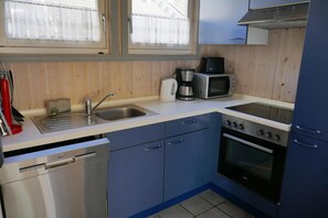 Una cocina compacta equipada con lavavajillas, estufa, microondas y pileta.