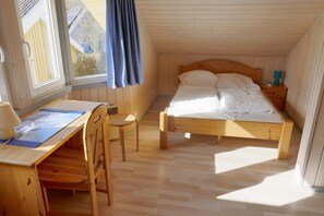 Una habitación con una cama de madera, un escritorio con silla y una ventana con cortinas.