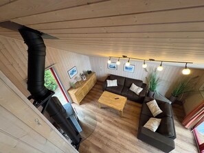 Una habitación acogedora con techo de madera, un sofá, una mesita de centro y una chimenea.