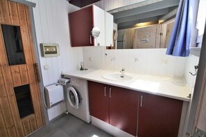 A compact bathroom with a washing machine, a sink, and a mirror.