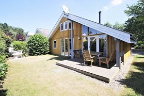 A wooden house with a patio, a satellite dish, and a chimney.