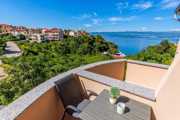 A balcony with a table, chairs, and a potted plant.