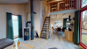 A spacious living area with a fireplace, a wooden staircase, and a dining area.