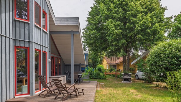 Un bâtiment moderne doté d’une terrasse, d’un espace salon extérieur et d’un grand arbre.