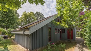 Un petit bâtiment d’un seul étage, doté d’un toit en pente, d’une porte rouge et d’une fenêtre.