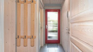 Un couloir en bois avec une porte rouge et une poignée en métal.