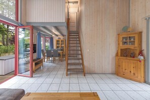 A spacious interior with a wooden staircase, a glass door leading outside, and a wooden cabinet with glass doors.