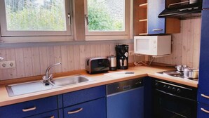A compact kitchen with wooden cabinets, a sink, a toaster, a coffee maker, a microwave, and a stove.