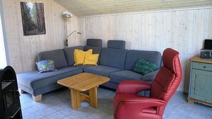 A living room with a grey sofa, a wooden coffee table, a red chair, and a small cabinet.