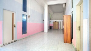 Corredor com portas à esquerda, um armário de madeira à direita e piso ladrilhado.