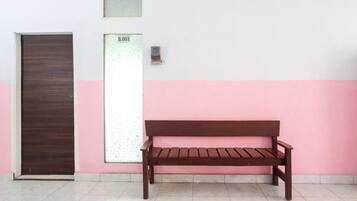 A wooden bench against a wall with a door and a wall-mounted device.